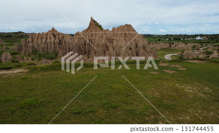 Layered Rock Formations and Grassy Plains Under Partly Cloudy Sky in Rural Wilderness Layered Rock Formations and Grassy Plains Under Partly Cloudy Sky in Rural Wilderness 131744455