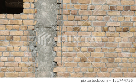 Close up of a brick wall with a concrete pillar and a dark opening on top 131744736