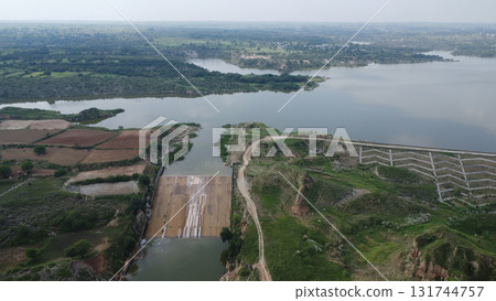 Aerial view of a dam and reservoir surrounded by lush green vegetation and farmland Aerial view of a dam and reservoir surrounded by lush green vegetation and farmland 131744757