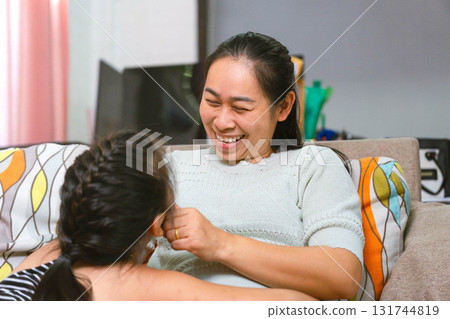 Asian Mother and Daughter Laughing Together on the Sofa at Home 131744819