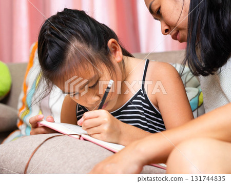 Asian Mother Teaching Her Daughter to Write at Home 131744835
