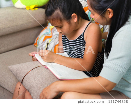 Asian Mother Teaching Her Daughter to Write at Home Asian Mother Teaching Her Daughter to Write at Home 131744838