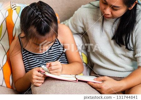 Asian Mother Teaching Her Daughter to Write at Home 131744841