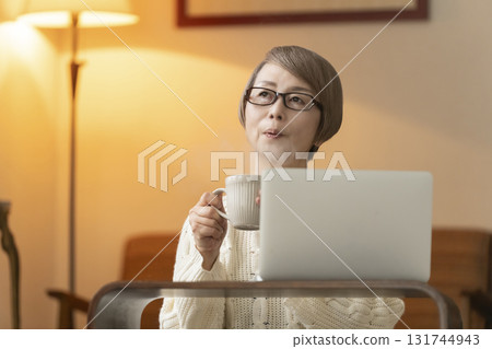 晚上,老年婦女在客廳裡用筆記型電腦聊天和閱讀 晚上,老年婦女在客廳裡用筆記型電腦聊天和閱讀 131744943