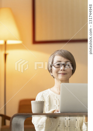 Senior women having conversations and reading on a laptop in the living room at night Senior women having conversations and reading on a laptop in the living room at night 131744948