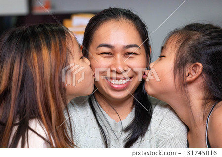 Happy Asian Mother Smiling While Daughters Kiss Her on Cheeks 131745016