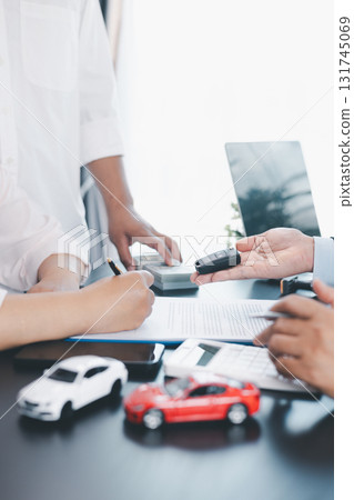 Customer receiving car key from dealer after signing contract, successful auto purchase and finance agreement at office desk, concept of vehicle loan, leasing, insurance or ownership. vehicle loan. Customer receiving car key from dealer after signing contract, successful auto purchase and finance agreement at office desk, concept of vehicle loan, leasing, insurance or ownership. vehicle loan. 131745069