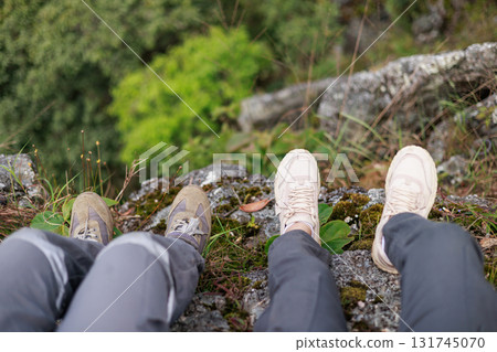 Close up of hiker resting on rocky cliff in hiking shoes, symbol of adventure, outdoor lifestyle, challenge, exploration, determination, nature journey and freedom in mountain travel. Close up of hiker resting on rocky cliff in hiking shoes, symbol of adventure, outdoor lifestyle, challenge, exploration, determination, nature journey and freedom in mountain travel. 131745070