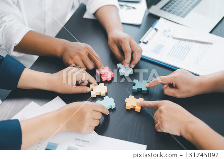 Business teamwork concept with people holding wooden puzzle pieces together, symbol of collaboration, strategy, problem solving, partnership and corporate success in modern office. business teamwork. 131745092