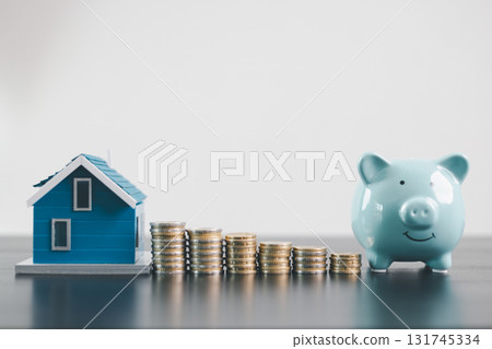 Mini house model with coins and blue piggy bank, representing mortgage loan, real estate investment, property finance, savings, insurance, wealth management and housing economy concept. Mini house model with coins and blue piggy bank, representing mortgage loan, real estate investment, property finance, savings, insurance, wealth management and housing economy concept. 131745334