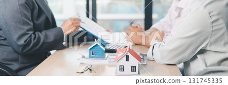 Mortgage consultation panorama with miniature house model in hand, financial advisor meeting clients, property investment, home loan agreement, real estate planning and housing business negotiation. Mortgage consultation panorama with miniature house model in hand, financial advisor meeting clients, property investment, home loan agreement, real estate planning and housing business negotiation. 131745335