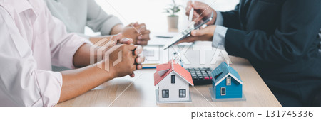 Mortgage consultation panorama with miniature house model in hand, financial advisor meeting clients, property investment, home loan agreement, real estate planning and housing business negotiation. Mortgage consultation panorama with miniature house model in hand, financial advisor meeting clients, property investment, home loan agreement, real estate planning and housing business negotiation. 131745336