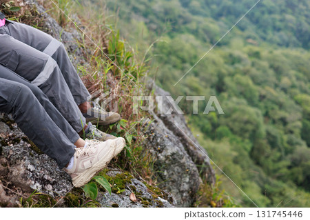 Close up of hiker resting on rocky cliff in hiking shoes, symbol of adventure, outdoor lifestyle, challenge, exploration, determination, nature journey and freedom in mountain travel. 131745446