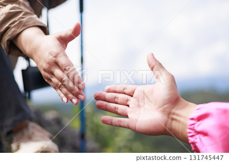 Close-up of hiker reaching out hand for support on rocky mountain, symbol of teamwork, leadership, trust, helping, motivation, encouragement, success and outdoor adventure lifestyle. Close-up of hiker reaching out hand for support on rocky mountain, symbol of teamwork, leadership, trust, helping, motivation, encouragement, success and outdoor adventure lifestyle. 131745447