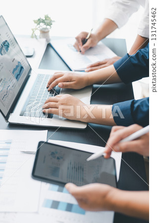Business data analysis concept with colleagues reviewing financial report on laptop, pointing at chart with growth graph, teamwork discussing statistics, planning strategy and corporate success. 131745462