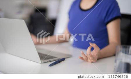 Adult Asian businesswoman practicing mindfulness meditation at desk with laptop promoting calm focus stress relief work life balance wellness in office 131746226