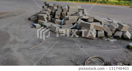 Gray bricks scattered on dusty asphalt ground with wire and road in background at urban construction area Gray bricks scattered on dusty asphalt ground with wire and road in background at urban construction area 131746403