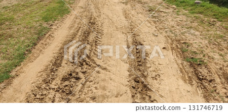 Aerial view of a dirt road with tire tracks running through it and grassy edges around it Aerial view of a dirt road with tire tracks running through it and grassy edges around it 131746719