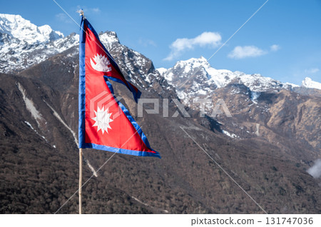 Nepali flag blowing by the wind against the blue sky in Langtang national park, Nepal. The crimson red is Nepal's national color, and it indicates the brave spirits of the Nepalese people. Nepali flag blowing by the wind against the blue sky in Langtang national park, Nepal. The crimson red is Nepal's national color, and it indicates the brave spirits of the Nepalese people. 131747036
