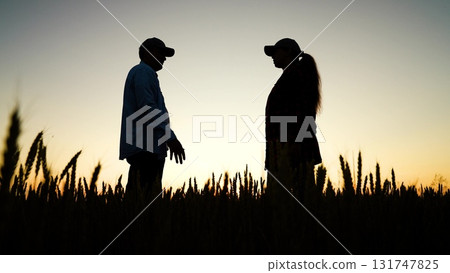 woman reviewing tablet while standing in wheat field., woman collaborating with tablet in rolling wheat field., farmer man and woman monitor tablet for wheat harvest planning., farmer woman and man 131747825