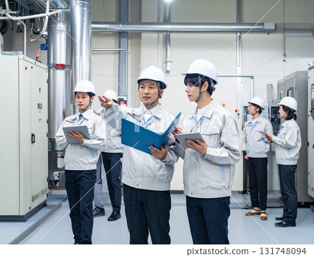 Image of workers inspecting factory equipment 131748094