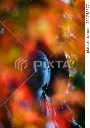 Smiling Jizo statue surrounded by autumn leaves Smiling Jizo statue surrounded by autumn leaves 131748377
