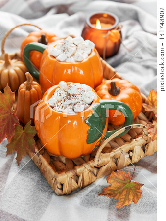 Warming pumpkin mugs filled with hot chocolate and marshmallows Warming pumpkin mugs filled with hot chocolate and marshmallows 131748902