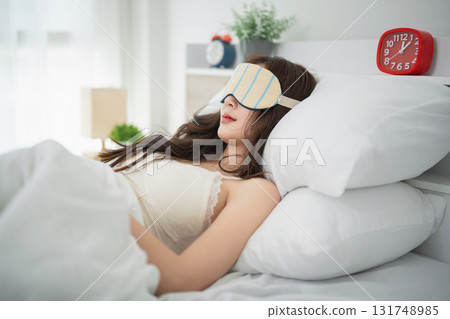 Woman Relaxing in Bed with Eye Mask, Peaceful Sleep Environment, Cozy Bedroom with Bright Light and Soft Bedding Accents Woman Relaxing in Bed with Eye Mask, Peaceful Sleep Environment, Cozy Bedroom with Bright Light and Soft Bedding Accents 131748985