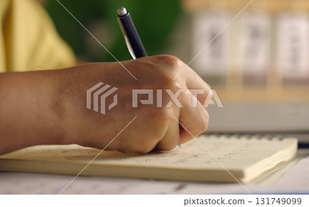 Asian woman works from home, surrounded by notes, a laptop, and messages. She browses the internet, writes ideas, and researches for her startup, utilizing wireless technology. Asian woman works from home, surrounded by notes, a laptop, and messages. She browses the internet, writes ideas, and researches for her startup, utilizing wireless technology. 131749099