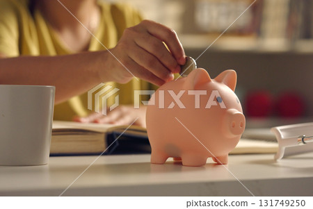Close up of asian woman put coins into piggy bank. 131749250