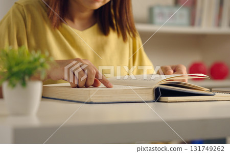 Close up of Asian woman reading a book on desk at home. Lifestyle and education concept. 131749262