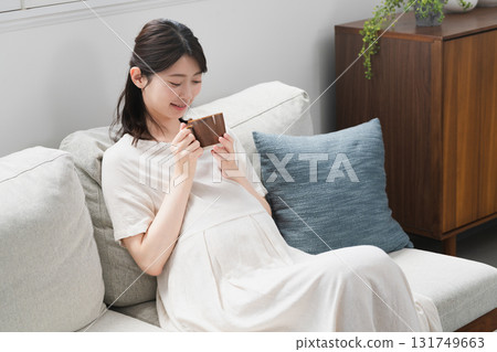 Pregnant woman drinking a drink on the sofa Lifestyle image 131749663