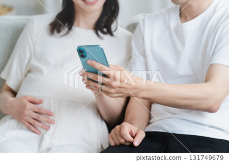 Pregnant woman and husband operating a smartphone Lifestyle image Pregnant woman and husband operating a smartphone Lifestyle image 131749679