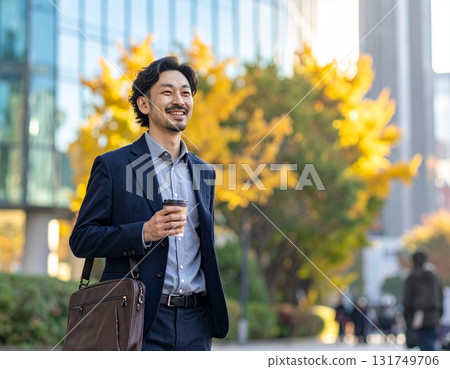 秋天，一位微笑的日本男子走過辦公區——城市早晨的場景，特寫他的通勤風格和臉部表情 131749706