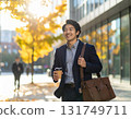 Smiling Japanese man walking through an office district in autumn - urban morning scene with close-up of his commuter style and facial expression 131749711