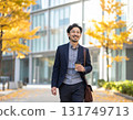 Smiling Japanese man walking through an office district in autumn - urban morning scene with close-up of his commuter style and facial expression 131749713