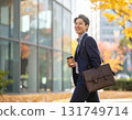 Smiling Japanese man walking through an office district in autumn - urban morning scene with close-up of his commuter style and facial expression 131749714