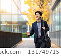 Smiling Japanese man walking through an office district in autumn - urban morning scene with close-up of his commuter style and facial expression 131749715