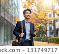 Smiling Japanese man walking through an office district in autumn - urban morning scene with close-up of his commuter style and facial expression 131749717