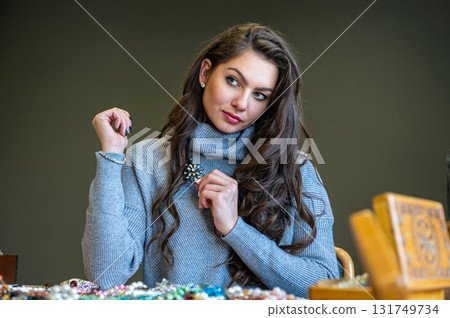 reflection of a woman in mirror choosing and trying different jewelry, soft focus, closeup 131749734