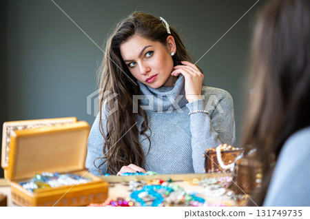reflection of a woman in mirror choosing and trying different jewelry, soft focus, closeup reflection of a woman in mirror choosing and trying different jewelry, soft focus, closeup 131749735