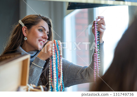 reflection of a woman in mirror choosing and trying different jewelry, soft focus, closeup reflection of a woman in mirror choosing and trying different jewelry, soft focus, closeup 131749736