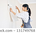 A young female carpenter putting up wallpaper during interior construction work in a house, focusing on her facial expression and hands 131749768