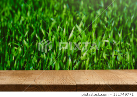 Wooden tabletop set against a vibrant green grass background in bright daylight Wooden tabletop set against a vibrant green grass background in bright daylight 131749771