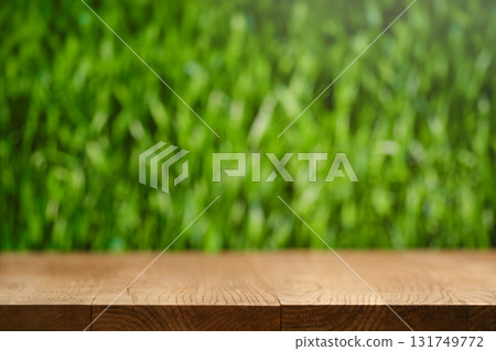 Wooden surface with blurred green grass background in a natural outdoor setting 131749772