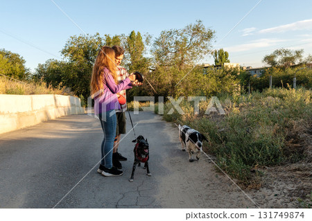 Man and daughter walking dogs on rural roadside 131749874