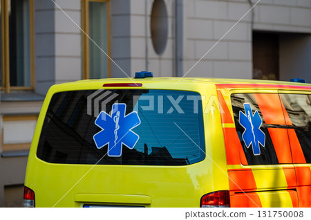 a yellow ambulance emergency car parked on the side of a crowded street, close up, selective focus 131750008