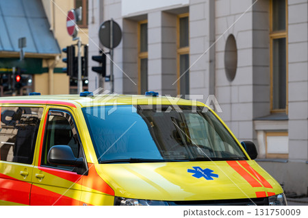 a yellow ambulance emergency car parked on the side of a crowded street, close up, selective focus 131750009