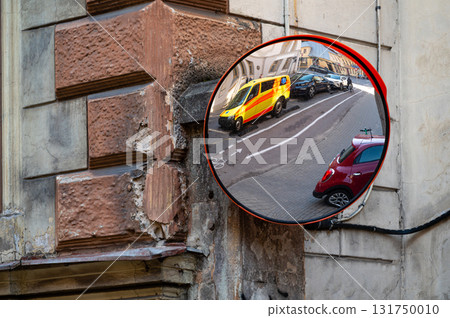 a traffic mirror with a yellow ambulance emergency car parked on the side of the street 131750010