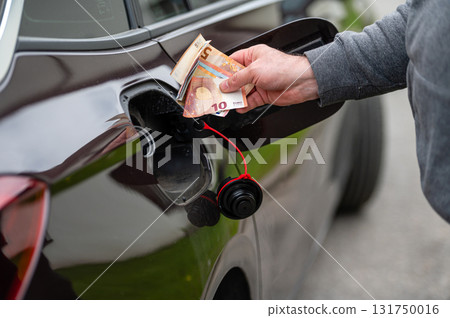 hand of man that puts money into the tank of car, close up, concept of expensive fuel, fuel crisis hand of man that puts money into the tank of car, close up, concept of expensive fuel, fuel crisis 131750016